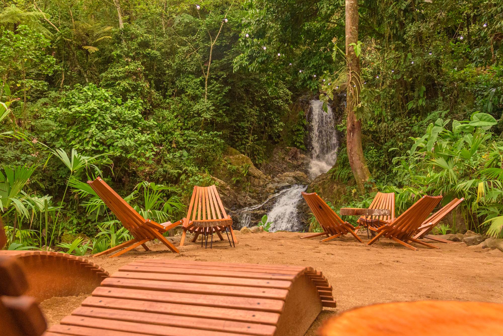 Sillas de madera frente a la cascada en El Fin del Estrés Doncello